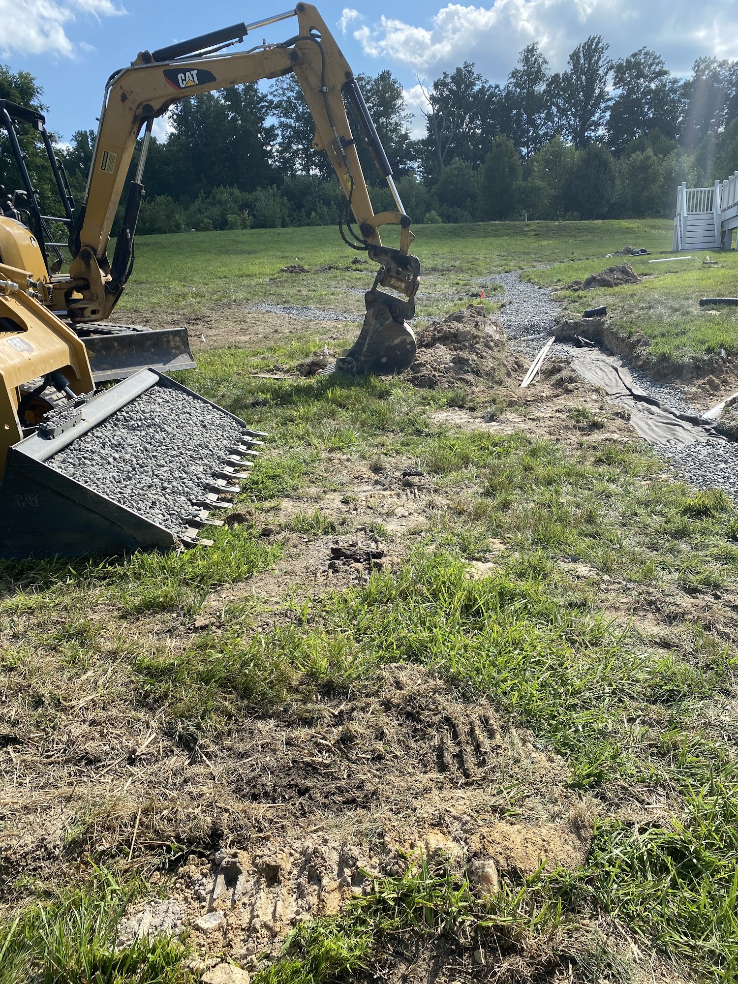 Excavator grading a backyard drainage area